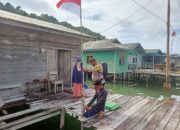 Potret Bhabinkamtibmas Bripka Mauliyadi Bagikan Bendera Merah Putih ke Warga Kampung di Desa Kuala Maras Anambas