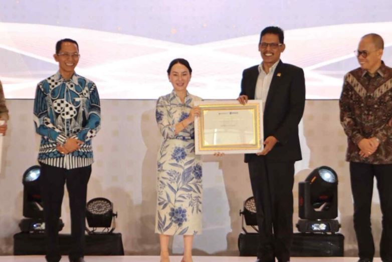 Li Claudia Chandra menyerahkan piagam penghargaan kepada Muhammad Kamaluddin disaksikan Amsakar Achmad.