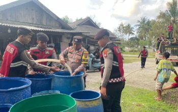 Personel Polres Natuna menyalurkan bantuan 8.000 liter air bersih ke rumah warga Desa Pengadah saat musim kemarau 2026.