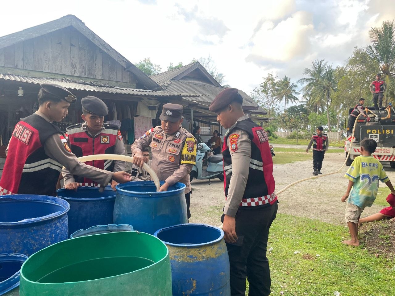 Personel Polres Natuna menyalurkan bantuan 8.000 liter air bersih ke rumah warga Desa Pengadah saat musim kemarau 2026.