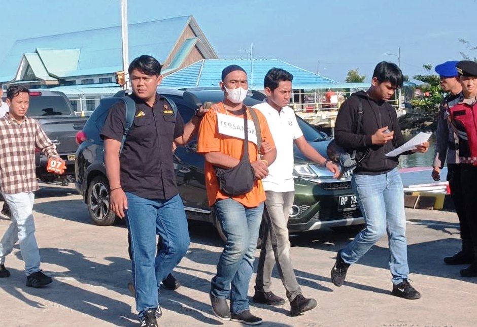 Tersangka DN saat melakukan rekonstruksi kasus pencurian perhiasan curian toko emas di Pelabuhan Natuna didampingi petugas kepolisian.