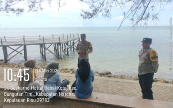 Personel Bhabinkamtibmas Polsek Bunguran Timur memberikan imbauan keselamatan dan warning kepada orang tua di tepi Pantai Piwang Natuna.
