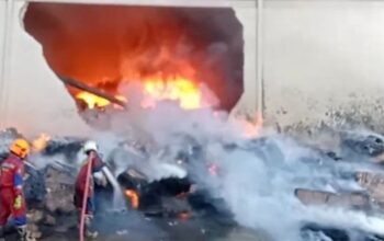 Petugas damkar berusaha memadamkan api yang membakar gudang pabrik di Citra Buana 3 Batam hingga dindingnya jebol