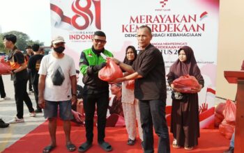 Direktur First Club Lian Tasrin secara simbolis menyerahkan paket kebutuhan pokok kepada pengemudi ojek online saat aksi sosial kemerdekaan.