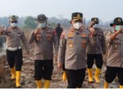 Kapolres Lingga dan petugas kepolisian menyiram sisa bara kebakaran lahan gambut di Singkep Barat yang berjarak 500 meter dari rumah warga