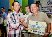 Wali Kota Batam, Amsakar Achmad, menyerahkan insentif saat menghadiri Silaturahmi bersama RT/RW, LPM, dan Tokoh Masyarakat se-Kecamatan Sekupang di Aula SMP Kartini Sei Harapan, Kecamatan Sekupang, Minggu (4/10/2026) malam.